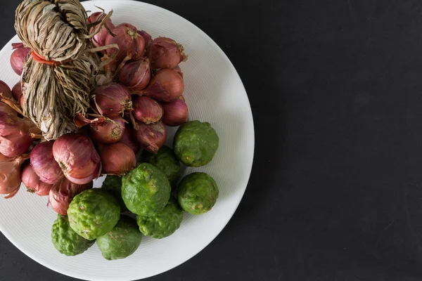 Bergamot and shallot in a plate on black background — Stock Photo, Image