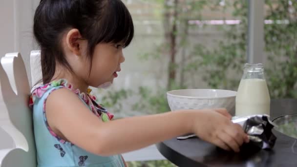 Kleines Mädchen mixt Müsli mit Milch und isst sie zum Frühstück zu Hause. — Stockvideo