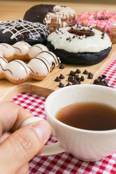 Tasse à café tenue à la main pendant la pause café beignet ou beignet — Photo