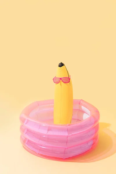 黄色の背景にサングラスをかけたバナナ型のインフレータブルバナナの子供用プール 垂直画像 — ストック写真
