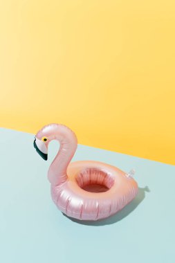 pink flamingo shaped inflatable on a blue and yellow background. Summer holiday and travel concept background. vertical image with copy space