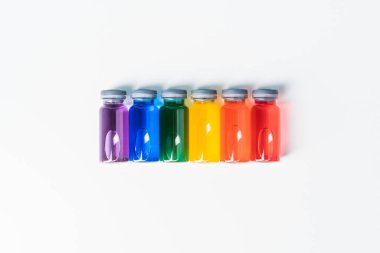 Beyaz bir arka planda izole edilmiş gökkuşağı renkli sıvı içeren cam şişeler. Aşı konsepti ve covid. Boşluğu kopyala