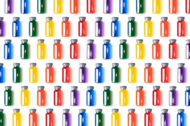 Beyaz zemin üzerinde gökkuşağı renkli sıvı bulunan cam şişelerin deseni. Aşı ve covid konsept..