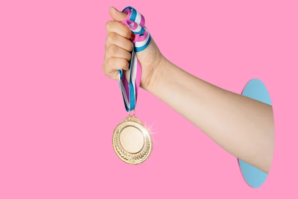 ピンクの背景に金メダルを保持する女性の手 賞と勝利の概念 Copyスペース — ストック写真