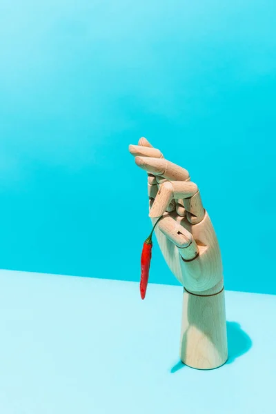 Hölzerne Hand Die Eine Rote Chilischote Auf Blauem Hintergrund Hält — Stockfoto