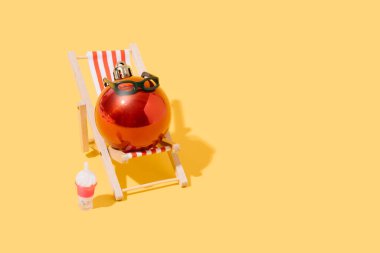 A christmas ball sunbathing on a beach chair. concept of summer, travel and christmas. 3d illustration. copy space clipart