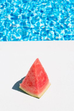Havuz kenarında bir dilim karpuz. Yaz, tatil ve yemek konsepti