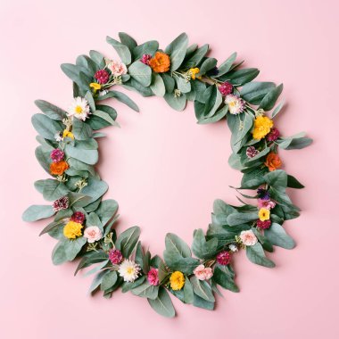 Pembe pastel arka planda farklı çiçeklerden oluşan yuvarlak bir çerçeve. Kopya alanı ile üst görünüm modellemesi.