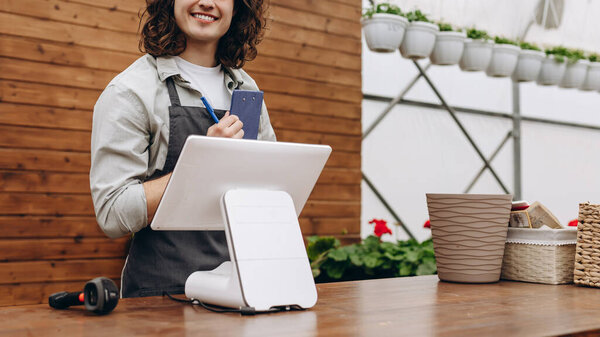 Attractive male florist and standing near cash register, waiting for clients in flower shop