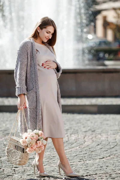 通りを歩く花のきれいな妊婦さん 茶色の目をした美しいブロンドの女の子 プロの化粧品 幸せで気楽な妊娠 春の通り — ストック写真