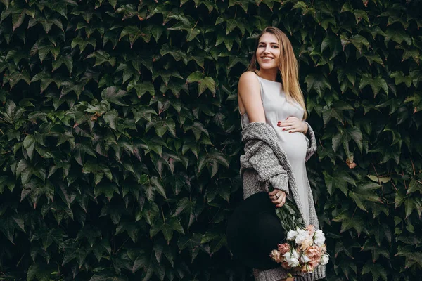 Muur Van Groene Bladeren Zwangere Vrouw Met Witte Bloemen Kijken — Stockfoto