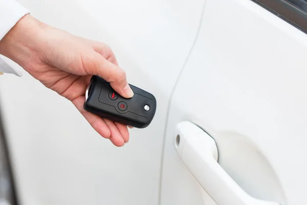 Main féminine ouvrir la voiture blanche sur le système de clé automatique . — Photo