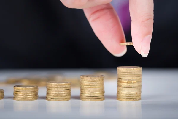 Close-up van mannenhand vulling geld stapel op gouden munten balk. — Stockfoto