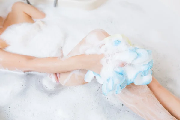 Mooi meisje douchen en benen wassen in badkuip. — Stockfoto