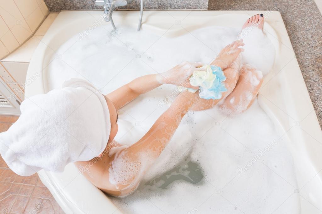 Bella ragazza sotto la doccia e lavarsi le mani nella vasca da bagno ... La vasca nella vasca