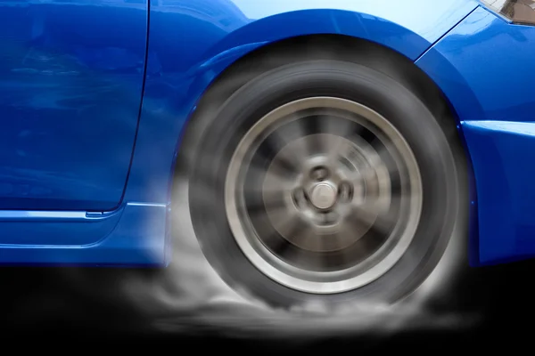 Blue car racing spinning wheel burns rubber on floor. — Stock Photo, Image
