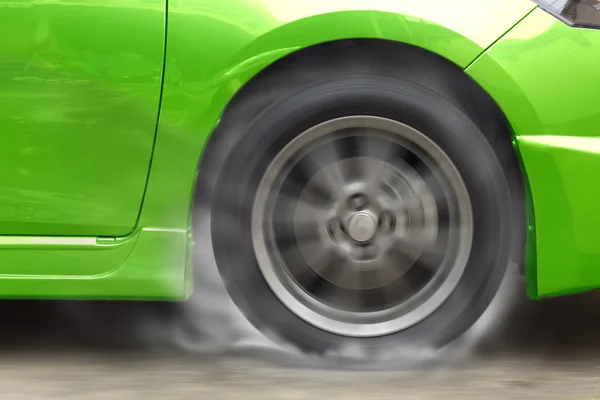 Roue de course automobile verte brûle caoutchouc sur le sol . — Photo