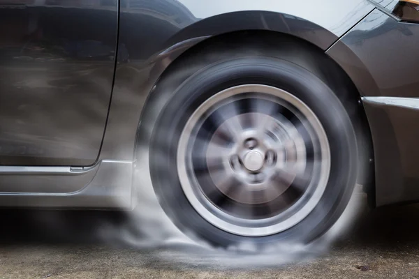 Auto závodní Kolovrat pálí gumy na podlaze. — Stock fotografie