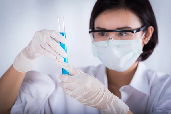 Científico mirando el tubo de ensayo azul en el laboratorio . —  Fotos de Stock