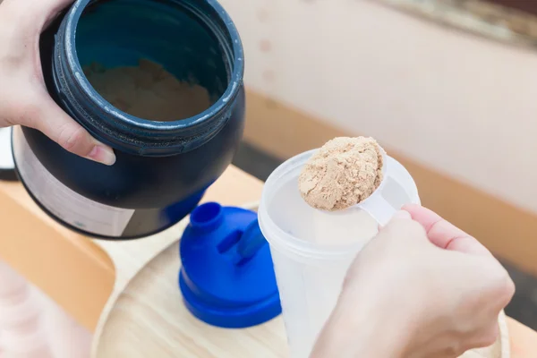 Scoop of whey protein on a wooden plate with jar. — Stock Photo, Image