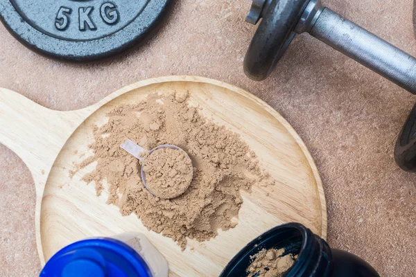 Una cucharada de proteína de suero en un plato de madera con frasco. en la vista superior —  Fotos de Stock