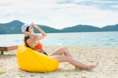 Yaz yaşam tarzı bronzlaşmış seksi vücutlu mutlu genç kız. Tropik ada plajı. Şık bikini ve güneş gözlüğü takıyor..