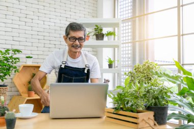Kıdemli bahçıvan bilgisayarı kullanıyor. Evde kahve eşliğinde film izliyor..