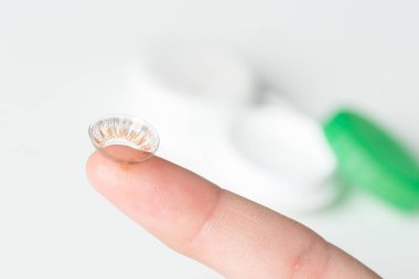 Bulanık arkaplanda kontak lensli parmak.