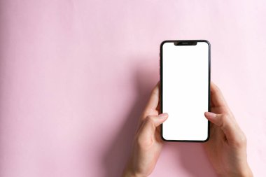 Telefonun yerleşim planı. Pembe pastel arka planda akıllı telefona dokunuşun üst görüntüsü. asgari kavram