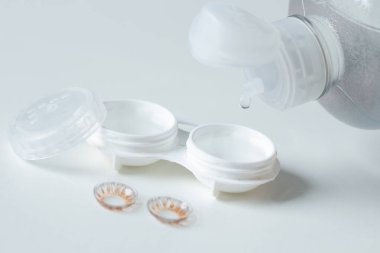 Kontakt lensler, çanta ve solüsyonlu beyaz arka plan. Göz sağlığı ve bakımı. Seçici odak