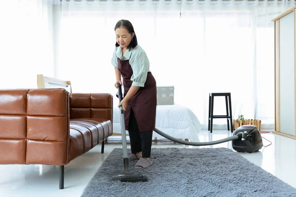 自宅で掃除機を使用してシニア女性 — ストック写真