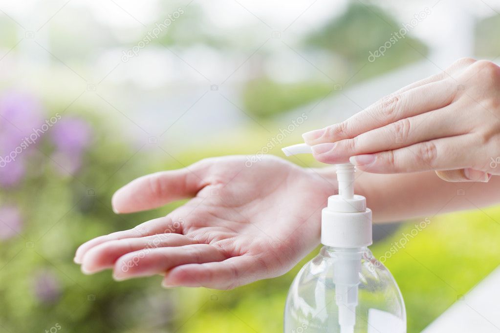 Female hands using wash hand sanitizer gel pump dispenser.