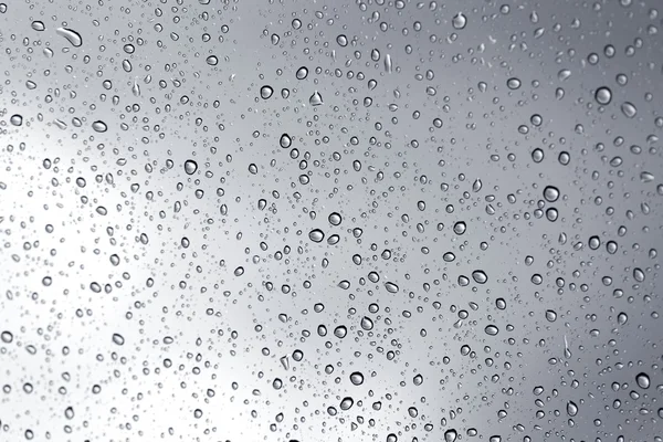 Goutte d'eau pluvieuse tempête sur fond miroir en verre . — Photo