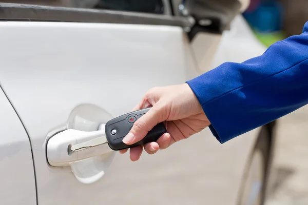 Ženská ruka otevřít bílé auto na klíč systému automatického. — Stock fotografie