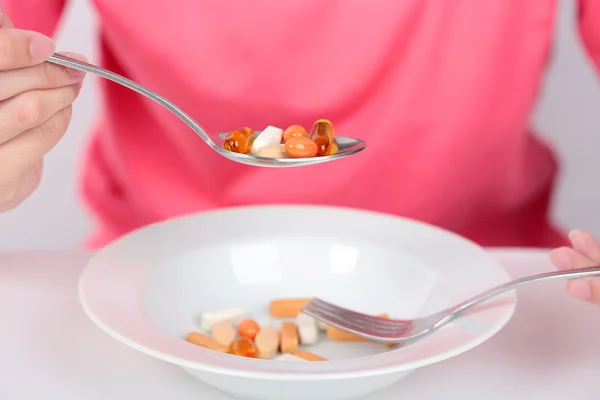 Mujeres jóvenes que comen cápsulas medicinales en cuchara para la salud . — Foto de Stock