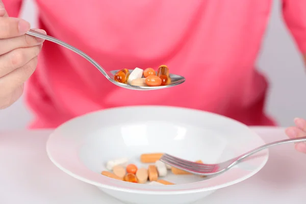 Mujeres jóvenes que comen cápsulas medicinales en cuchara para la salud . — Foto de Stock