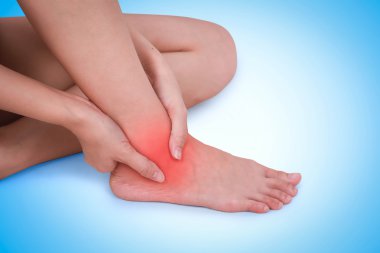 Close up suffering male pain in ankle on blue background. clipart