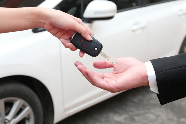 Mão feminina dando uma chave para comprador ou carro alugado . — Fotografia de Stock