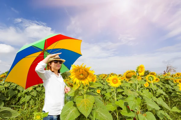 Eine Frau hält einen Regenschirm mit Sonnenblumenfeld in der Hand. — Stockfoto