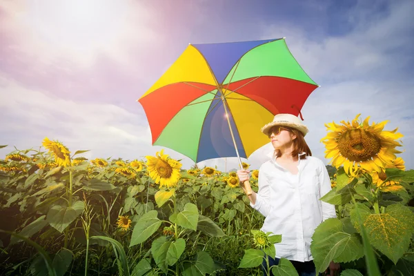 Eine Frau hält einen Regenschirm mit Sonnenblumenfeld in der Hand. — Stockfoto