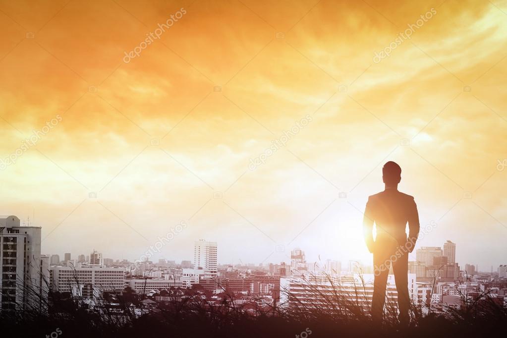 Silhouette of businessman to city way light the sunset.