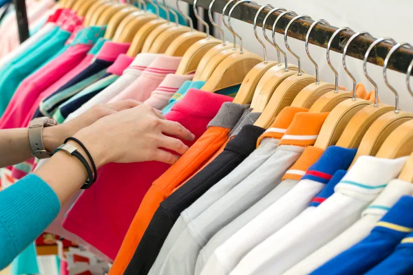 Mujer joven buscando nueva camisa de compras en la tienda . — Foto de Stock