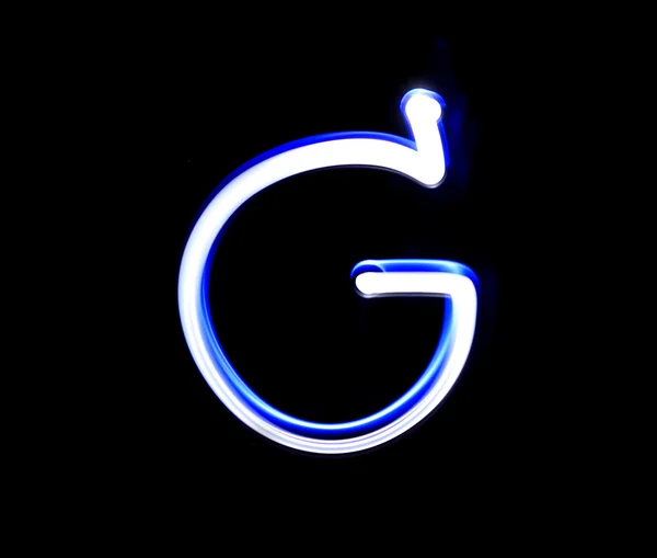 G George alphabet hand skriva blått ljus över svart bakgrund — Stockfoto