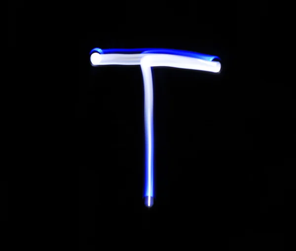 Rukou T Tango abeceda psaní modré světlo na černém pozadí. — Stock fotografie