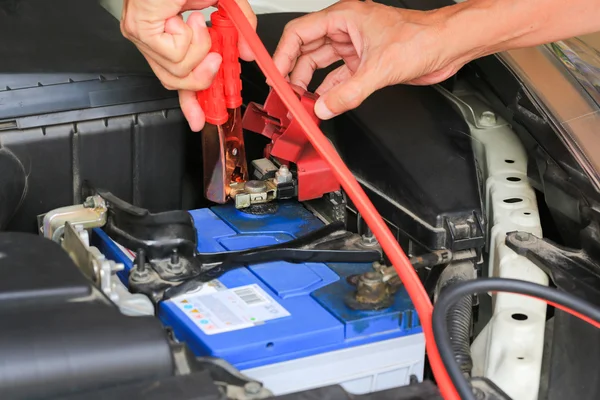 Автомеханик использует кабели перемычки аккумулятора заряда разряженной батареи . — стоковое фото