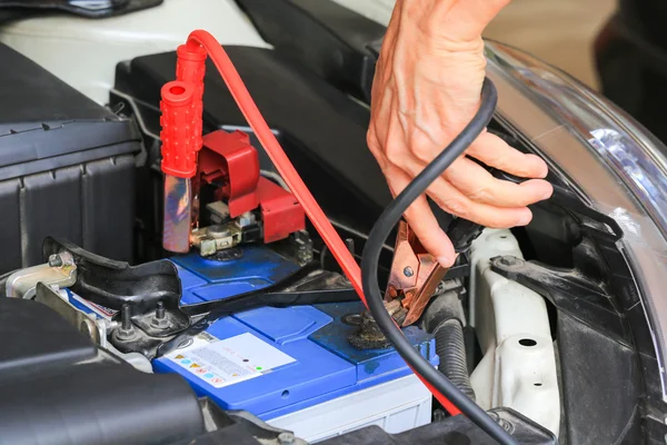Meccanico auto utilizza cavi batteria jumper caricare una batteria scarica . — Foto Stock