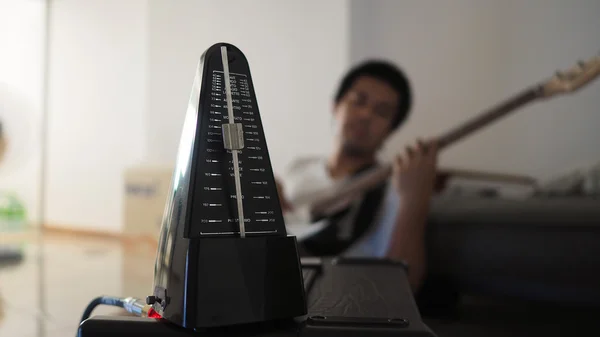 Black metronome is used by musician to help keep a steady tempo as he play, or to work on issues of irregular timing, or to help internalize a clear sense of timing and tempo. — Stock Photo, Image