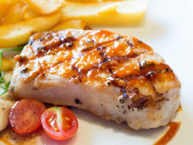 Domuz pirzolası. Izgara domuz biftek beyaz tabak içinde hizmet patates kızartması ve domates ile.