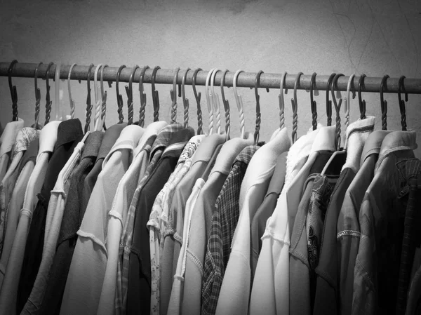 Askı raf üzerinde asılı elbiseleri siyah beyaz görüntü. Moda elbise askıları seçimi.