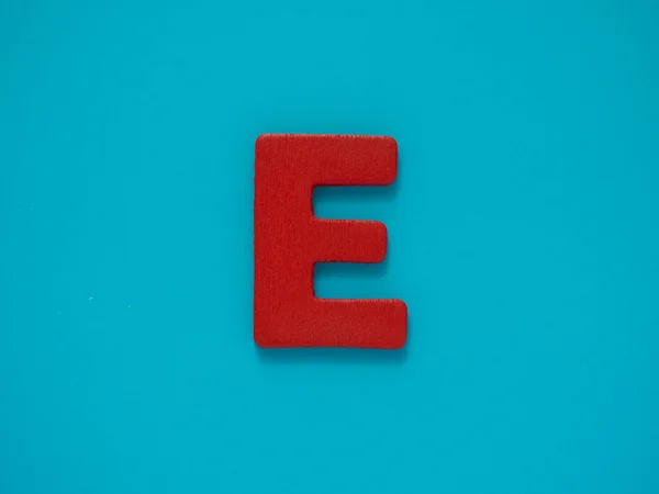 Velké písmeno E. červené písmeno E ze dřeva na modrém pozadí. Abeceda samohláska. — Stock fotografie